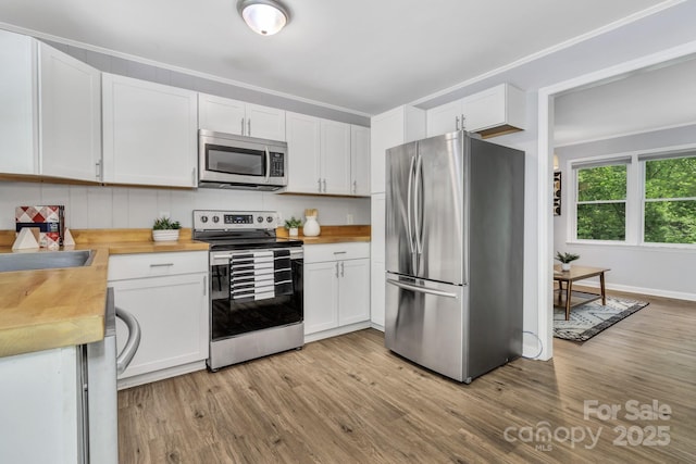 35 Avondale Rd, Asheville, NC 28803 - kitchen with appliances with stainless steel finishes, wooden counters, light wood finished floors, white cabinetry, and crown molding