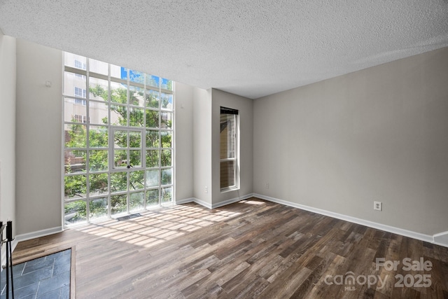 415 W 7th St Unit H, Charlotte, NC 28202 - unfurnished room featuring dark wood finished floors, healthy amount of natural light, a textured ceiling, and baseboards