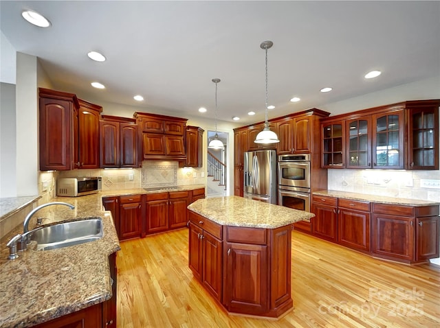 kitchen with stainless steel appliances, a sink, backsplash, light wood-style flooring, and recessed lighting