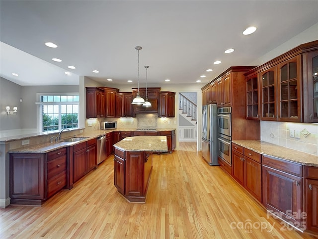 kitchen with a sink, appliances with stainless steel finishes, a kitchen island, tasteful backsplash, and light wood-style floors