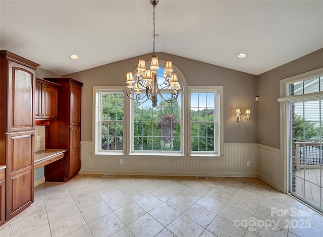 unfurnished dining area featuring a wainscoted wall, lofted ceiling, a chandelier, a desk, and recessed lighting