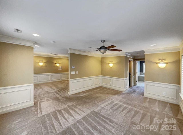 carpeted empty room with a decorative wall, ornamental molding, ceiling fan, a wainscoted wall, and recessed lighting