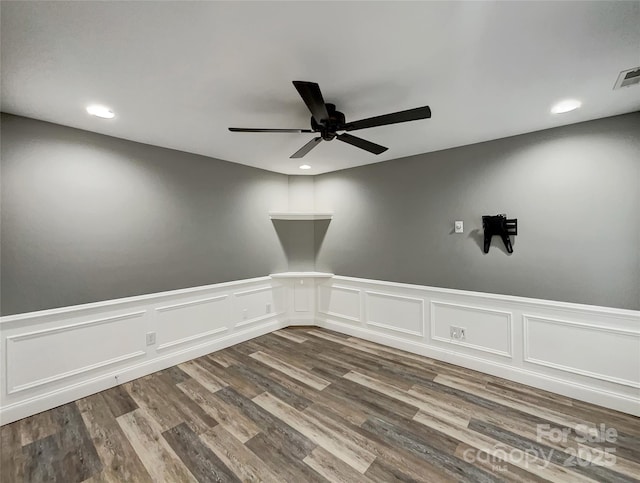 spare room featuring ceiling fan, a decorative wall, dark wood finished floors, recessed lighting, and a wainscoted wall