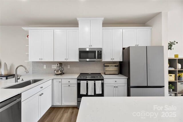 3748 Ellington St, Charlotte, NC 28211 - kitchen featuring appliances with stainless steel finishes, a sink, open shelves, light countertops, and light wood-style floors