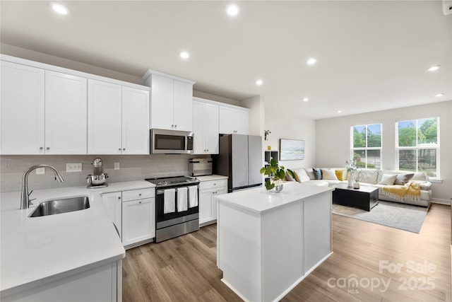 3748 Ellington St, Charlotte, NC 28211 - kitchen featuring stainless steel appliances, a sink, a center island, decorative backsplash, and light wood finished floors