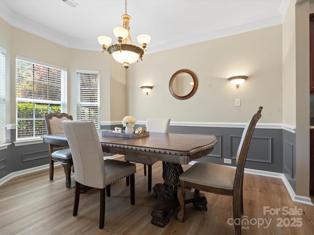 1051 Streamlet Way, Monroe, NC 28110 - dining room with light wood-style flooring, a chandelier, wainscoting, crown molding, and a decorative wall
