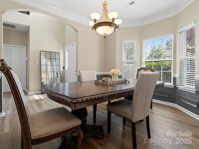 1051 Streamlet Way, Monroe, NC 28110 - dining area with arched walkways, light wood-style flooring, a chandelier, crown molding, and baseboards