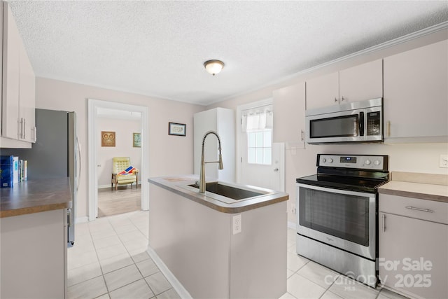 485 Lincoln St, Cramerton, NC 28032 - kitchen featuring stainless steel appliances, a sink, light tile patterned floors, a textured ceiling, and a center island with sink