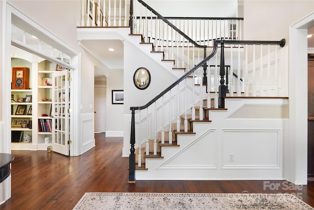 19946 River Falls Dr, Davidson, NC 28036 - staircase featuring built in shelves, a high ceiling, wood finished floors, crown molding, and a decorative wall