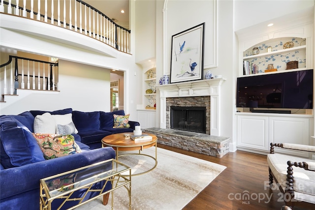 19946 River Falls Dr, Davidson, NC 28036 - living area featuring wood finished floors, built in shelves, stairway, a fireplace, and a towering ceiling