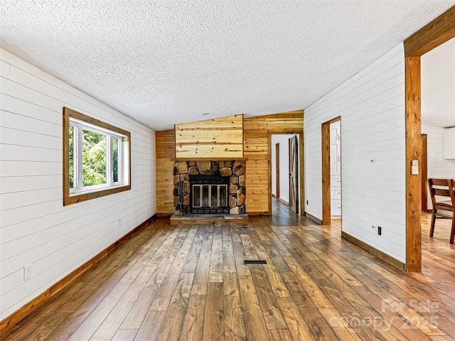 74 Saturn Ct, Clyde, NC 28721 - unfurnished living room featuring lofted ceiling, a textured ceiling, hardwood / wood-style flooring, wood walls, and baseboards