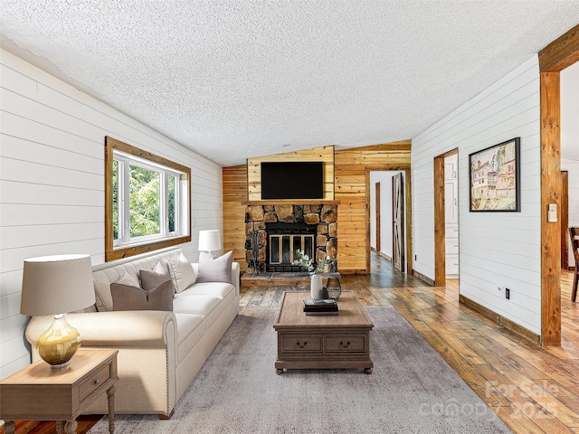 74 Saturn Ct, Clyde, NC 28721 - living area featuring wooden walls, a textured ceiling, lofted ceiling, wood-type flooring, and a fireplace