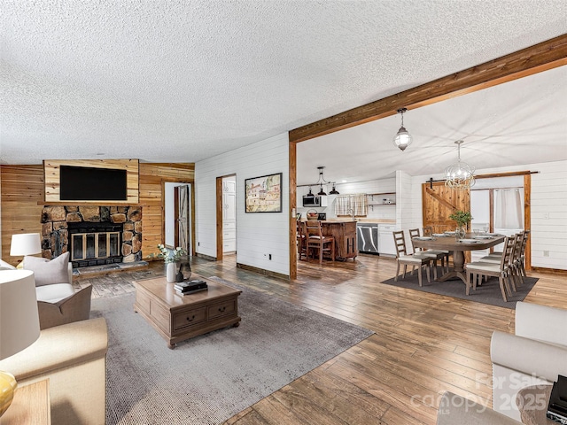 74 Saturn Ct, Clyde, NC 28721 - living area featuring wood walls, a chandelier, a textured ceiling, hardwood / wood-style floors, and a fireplace