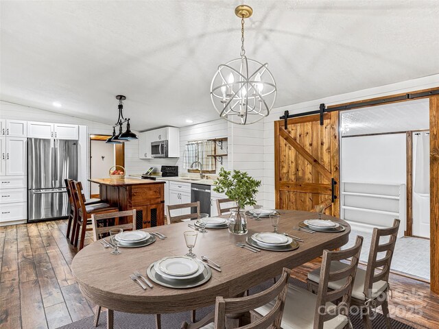 74 Saturn Ct, Clyde, NC 28721 - dining space featuring a barn door, hardwood / wood-style flooring, a chandelier, vaulted ceiling, and wooden walls