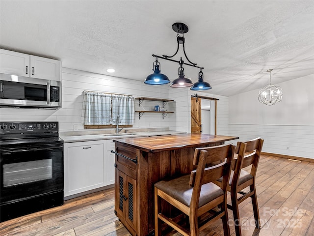 74 Saturn Ct, Clyde, NC 28721 - kitchen with stainless steel microwave, a barn door, black electric range oven, a sink, and butcher block countertops