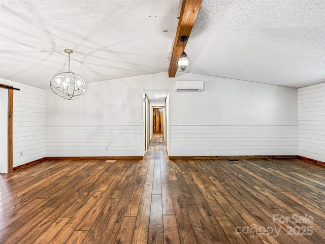 74 Saturn Ct, Clyde, NC 28721 - spare room featuring a wall mounted air conditioner, wood-type flooring, a textured ceiling, a barn door, and baseboards