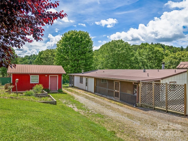 74 Saturn Ct, Clyde, NC 28721 - rear view of house featuring a garden, metal roof, and an outbuilding