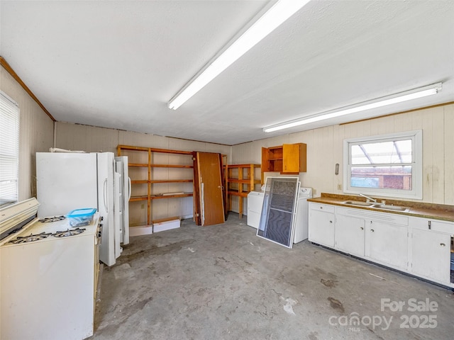 74 Saturn Ct, Clyde, NC 28721 - kitchen with a sink, unfinished concrete flooring, washing machine and clothes dryer, white cabinets, and open shelves