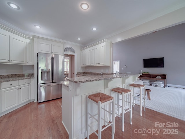 1508 Avalon Oaks Ct, Dallas, NC 28034 - kitchen featuring high quality fridge, ornamental molding, light wood-type flooring, white cabinetry, and a kitchen breakfast bar
