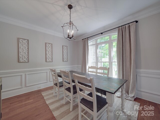 1508 Avalon Oaks Ct, Dallas, NC 28034 - dining area with a chandelier, crown molding, a wainscoted wall, light wood-type flooring, and a decorative wall
