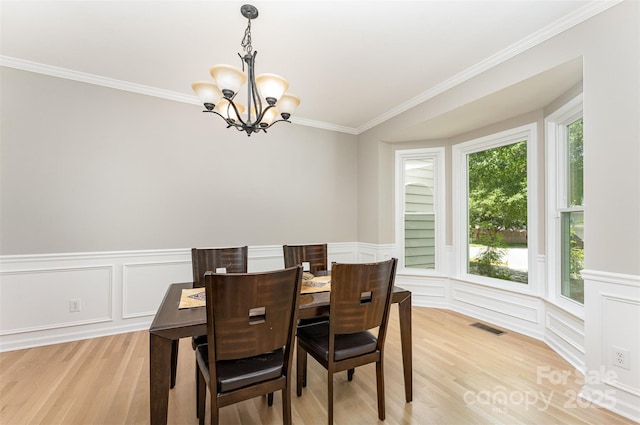 1147 Anduin Falls Dr, Charlotte, NC 28269 - dining area with a chandelier, a decorative wall, light wood-style floors, ornamental molding, and wainscoting