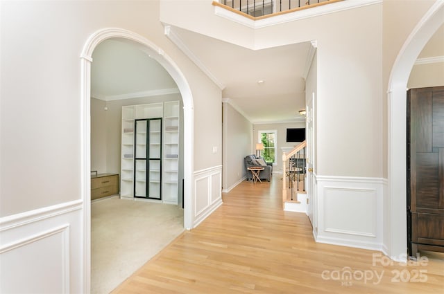 1147 Anduin Falls Dr, Charlotte, NC 28269 - hallway featuring crown molding, a decorative wall, wood finished floors, stairway, and arched walkways