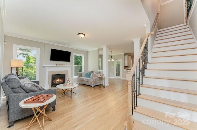 1147 Anduin Falls Dr, Charlotte, NC 28269 - living room with stairs, light wood-style floors, crown molding, and a warm lit fireplace