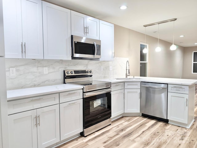 6756 Denver Heights Cir, Denver, NC 28037 - kitchen featuring appliances with stainless steel finishes, a sink, a peninsula, light wood finished floors, and tasteful backsplash