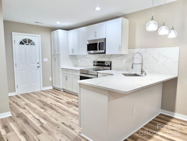 6756 Denver Heights Cir, Denver, NC 28037 - kitchen with stainless steel appliances, a sink, light stone counters, light wood-style flooring, and a peninsula