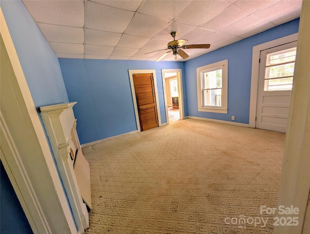 unfurnished bedroom with a paneled ceiling, carpet flooring, baseboards, and a ceiling fan