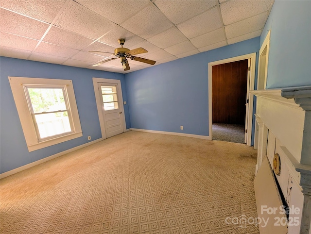 unfurnished room featuring a drop ceiling, baseboards, and a ceiling fan