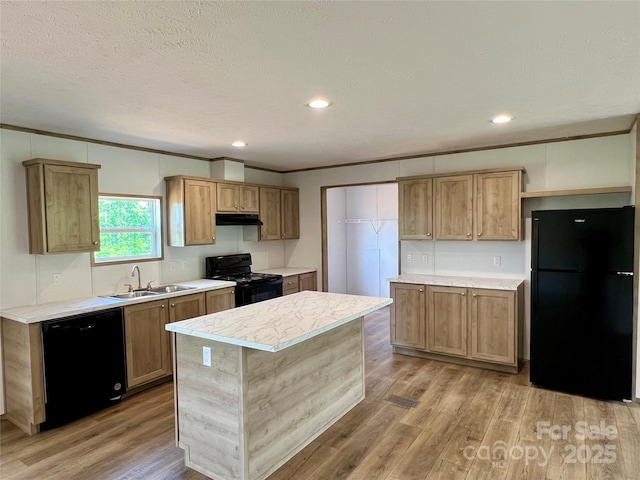 kitchen with black appliances, a sink, under cabinet range hood, light countertops, and light wood-type flooring