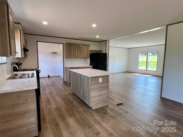kitchen featuring freestanding refrigerator, wood finished floors, a kitchen island, light countertops, and recessed lighting