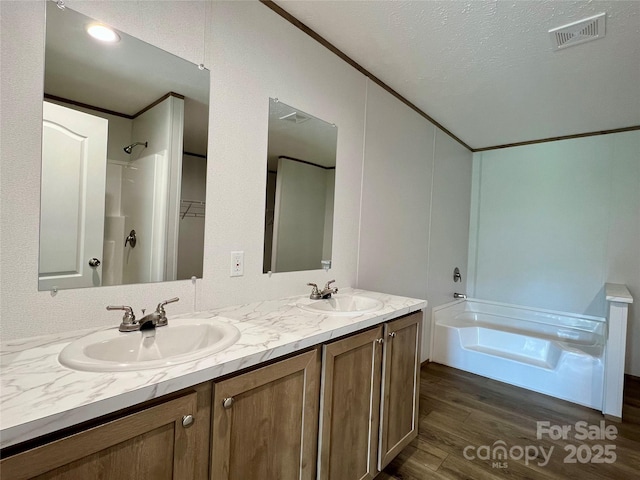 bathroom featuring wood finished floors, double vanity, a tub to relax in, ornamental molding, and a shower
