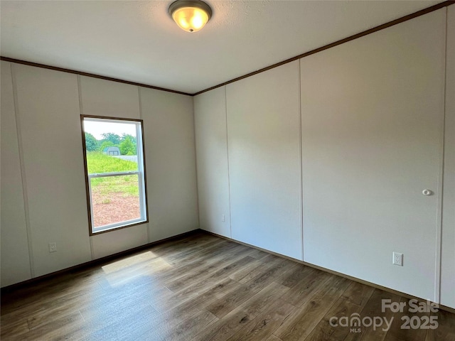 empty room featuring wood finished floors and crown molding