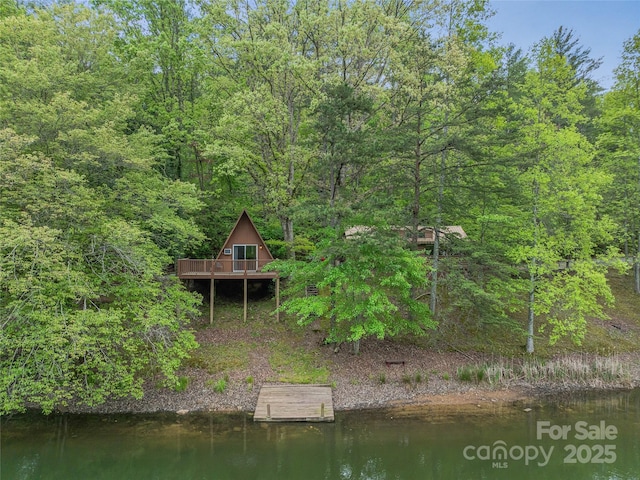 rear view of property featuring a deck with water view and a view of trees