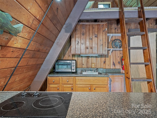 kitchen featuring black electric stovetop, a sink, dark countertops, wood walls, and wooden ceiling