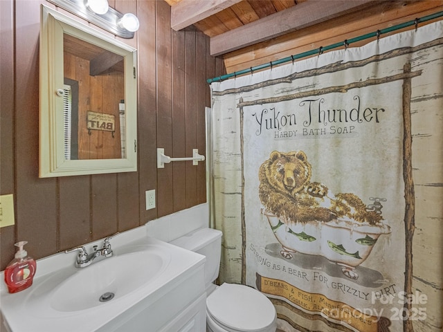 full bathroom with wooden ceiling with exposed beams, wooden walls, toilet, and vanity