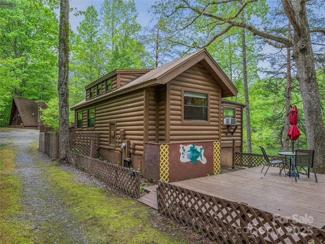view of home's exterior with a deck, outdoor dining space, cooling unit, and faux log siding