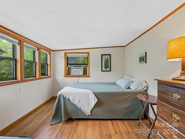 bedroom featuring wood finished floors, a textured ceiling, cooling unit, crown molding, and baseboards