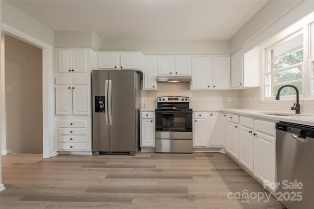 kitchen with stainless steel appliances, a sink, under cabinet range hood, and white cabinets