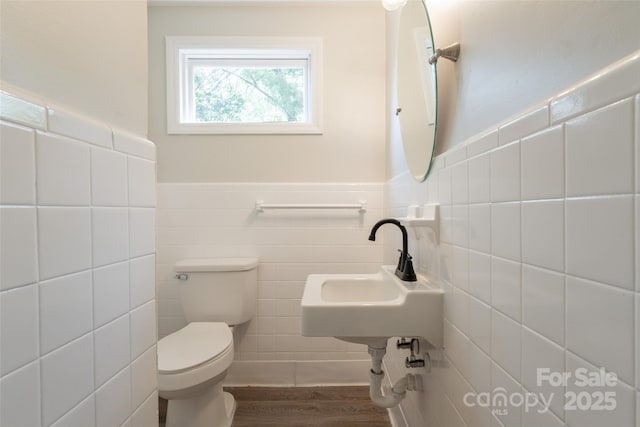 bathroom with tile walls, toilet, wood finished floors, and wainscoting