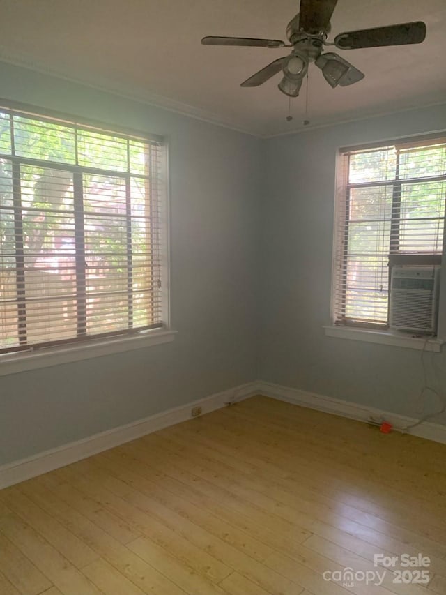 spare room featuring ornamental molding, light wood-style flooring, ceiling fan, baseboards, and cooling unit