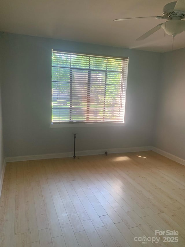 unfurnished room with healthy amount of natural light, wood finished floors, ceiling fan, and baseboards