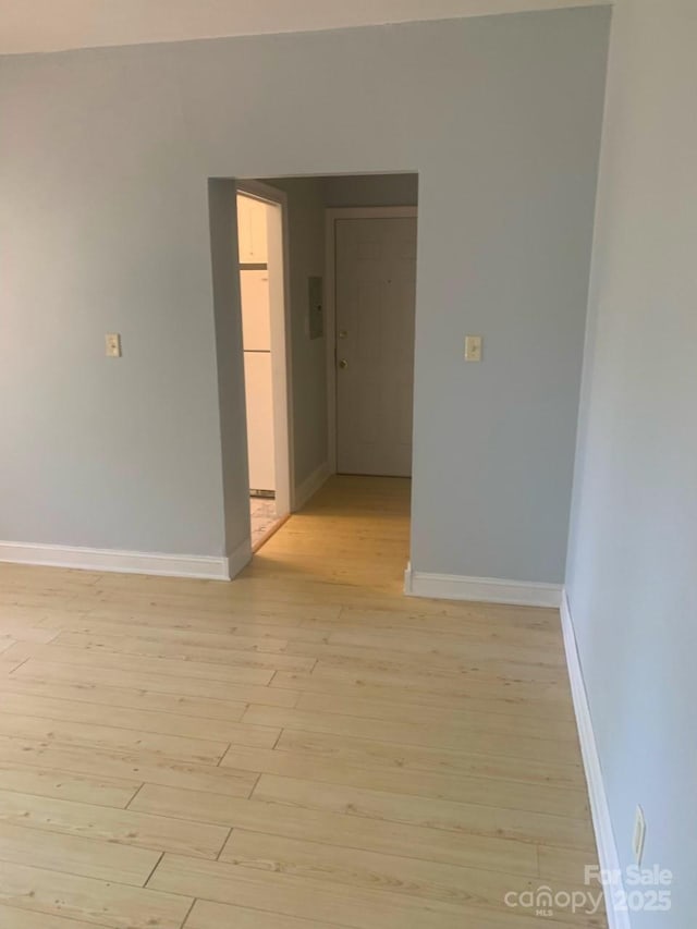 empty room featuring baseboards and light wood-type flooring