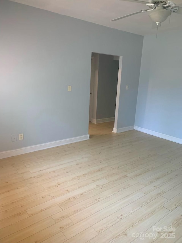 spare room featuring a ceiling fan, light wood-style floors, and baseboards