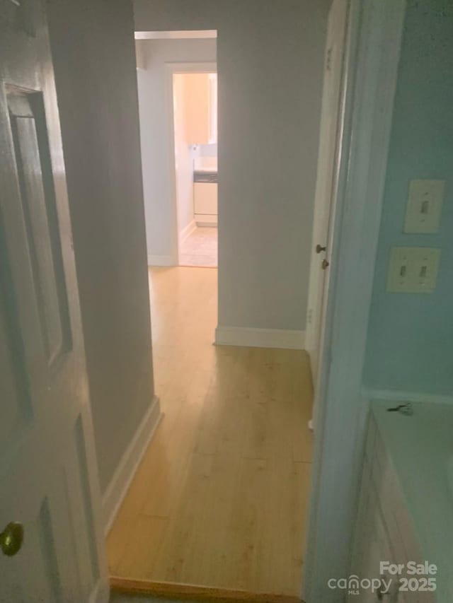 corridor featuring baseboards and light wood-type flooring