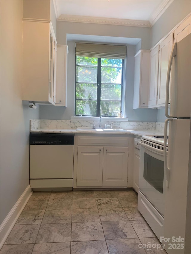 kitchen with white appliances, a sink, white cabinets, ornamental molding, and baseboards