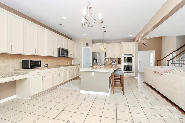 1618 Bay Meadows Ave NW, Concord, NC 28027 - kitchen featuring appliances with stainless steel finishes, open floor plan, decorative backsplash, a chandelier, and a kitchen bar