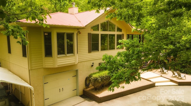 571 Ivy Ridge Cir, Sylva, NC 28779 - view of side of home featuring a garage, metal roof, a chimney, and stucco siding